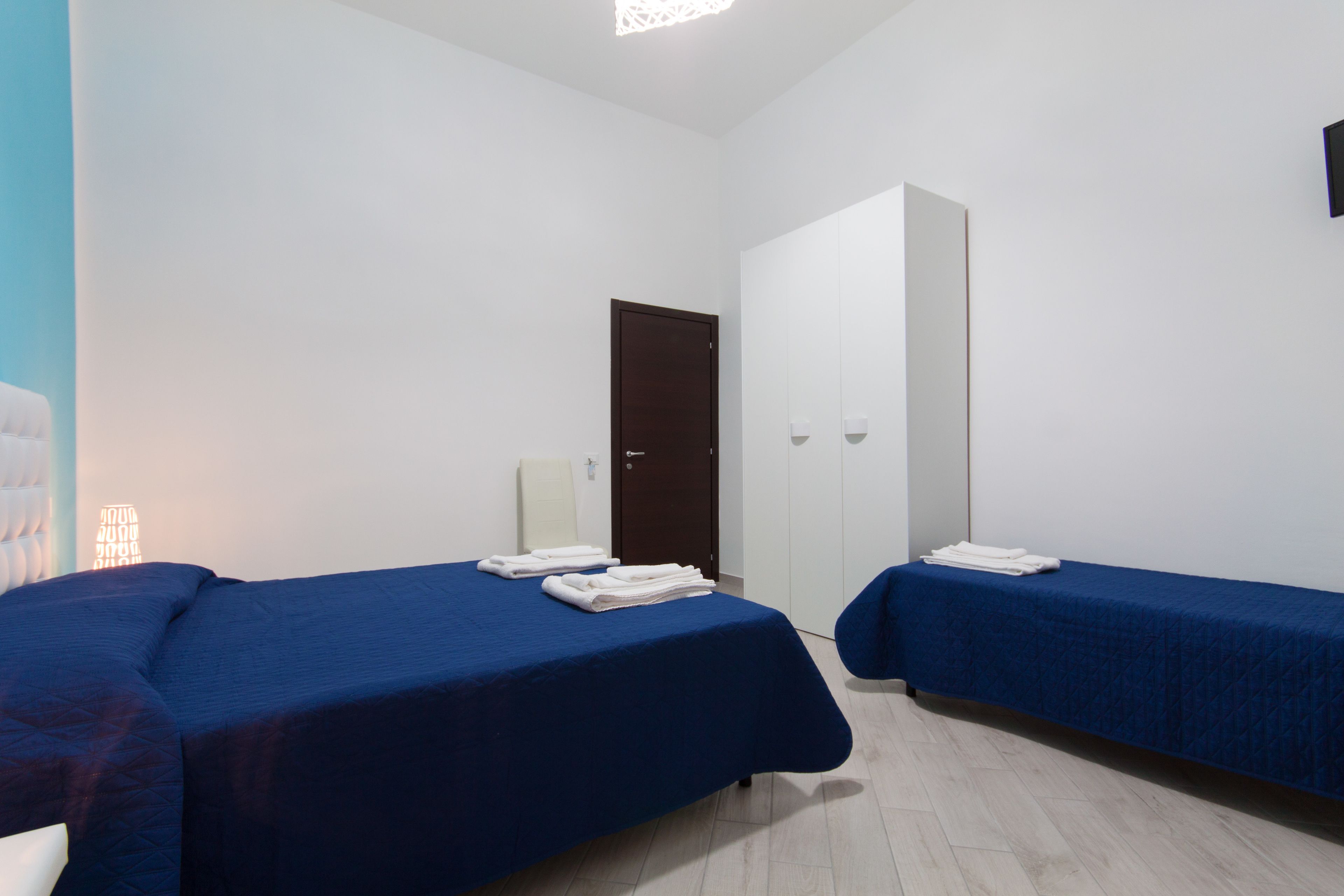 Ein Zimmer mit zwei Betten, einer Tür und einer weißen Wand.