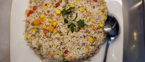 A plate of fried rice with mixed vegetables and a garnish of parsley.