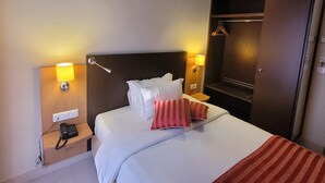 Ein Hotelzimmer mit Bett, Nachttischlampen, Telefon und Kleiderschrank.