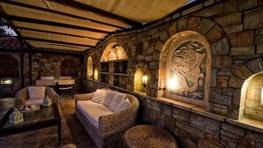 Una habitación con paredes de piedra, muebles de mimbre, chimenea e iluminación decorativa.