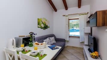 Un espacio habitable compacto con comedor, un sofá, televisión y ventana con vistas.