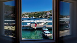 Vista desde una ventana sobre un puerto con barcos, un puente y una ciudad en la ladera.