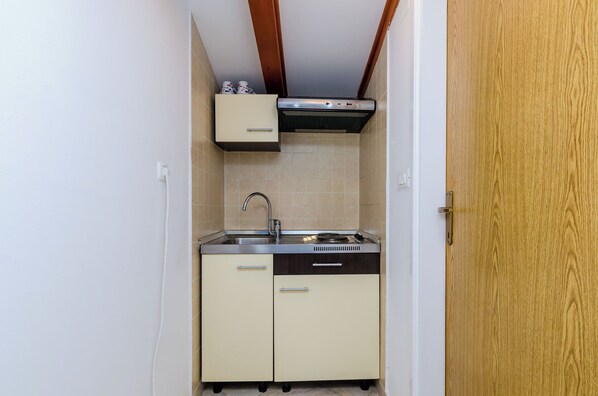 A compact kitchen with a built-in dishwasher, a sink, and a small cabinet. - Orka Apartments (Dubrovnik)