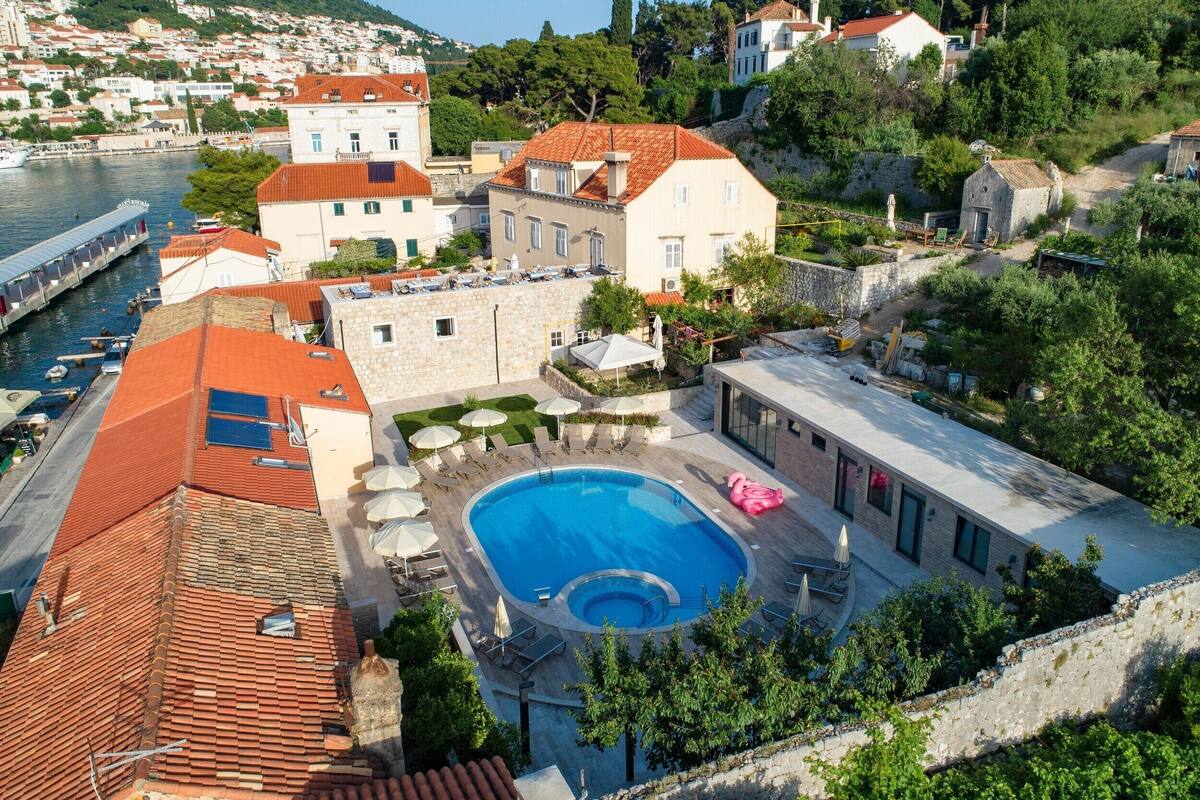 A residential area with a swimming pool, outdoor seating, and a view of the sea.