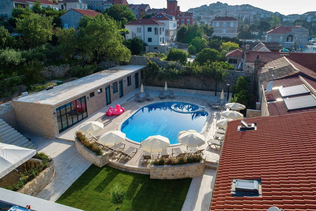 A residential area with a swimming pool, lounge chairs, and a stone building.
