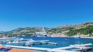 Una marina con barcos amarrados, un ferry y un paisaje montañoso al fondo.