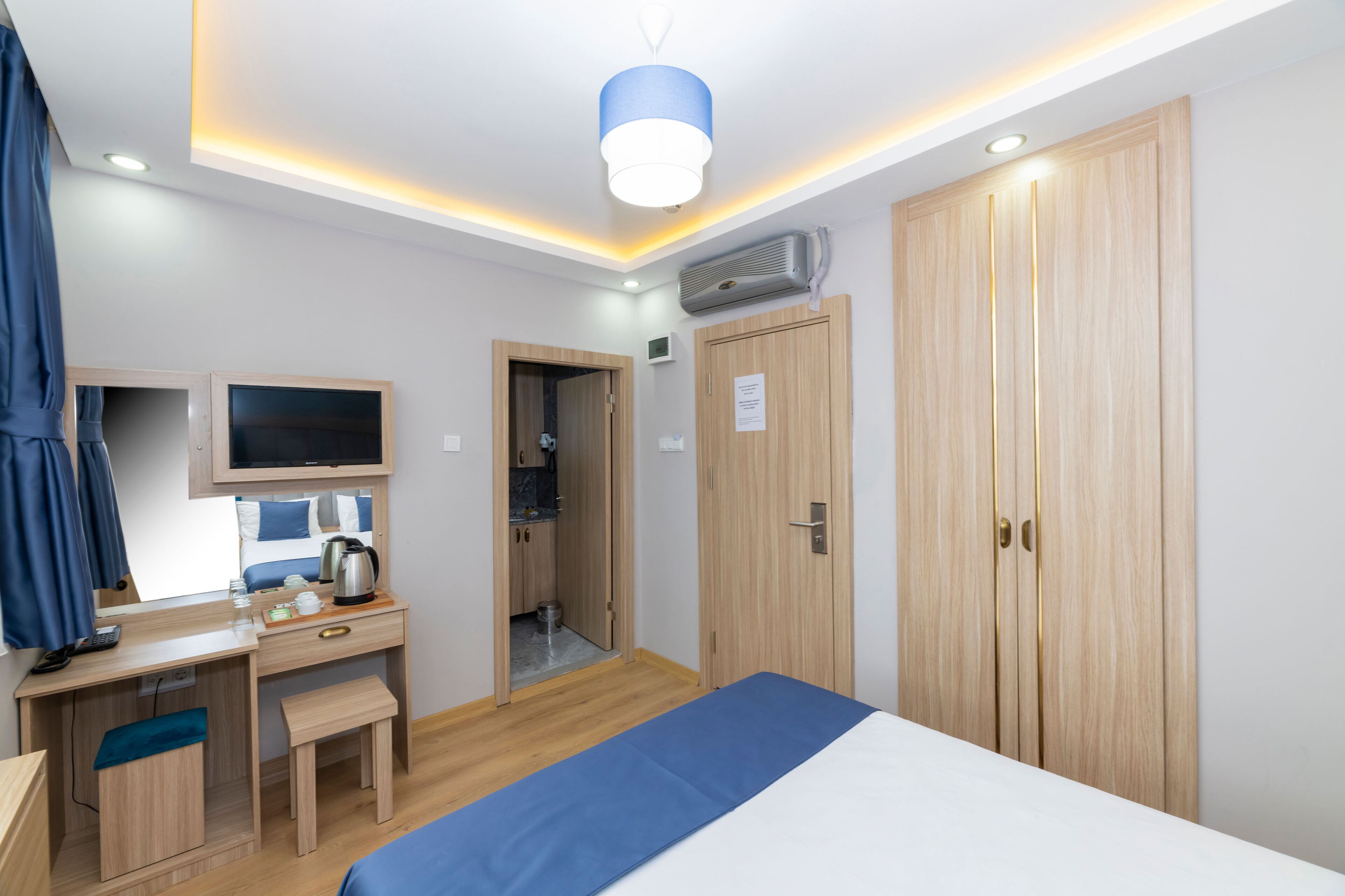 A modern hotel room with a bed, desk, and wardrobe.