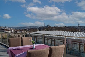 A rooftop terrace with a table set for two, overlooking a cityscape with historical buildings and a mosque. - Yesilpark Hotel (Istanbul)