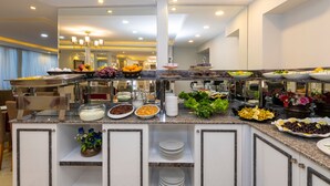 A buffet with various food items and a mirror reflecting the room.