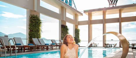 Una piscina al aire libre, sombrillas, sillones reclinables de piscina