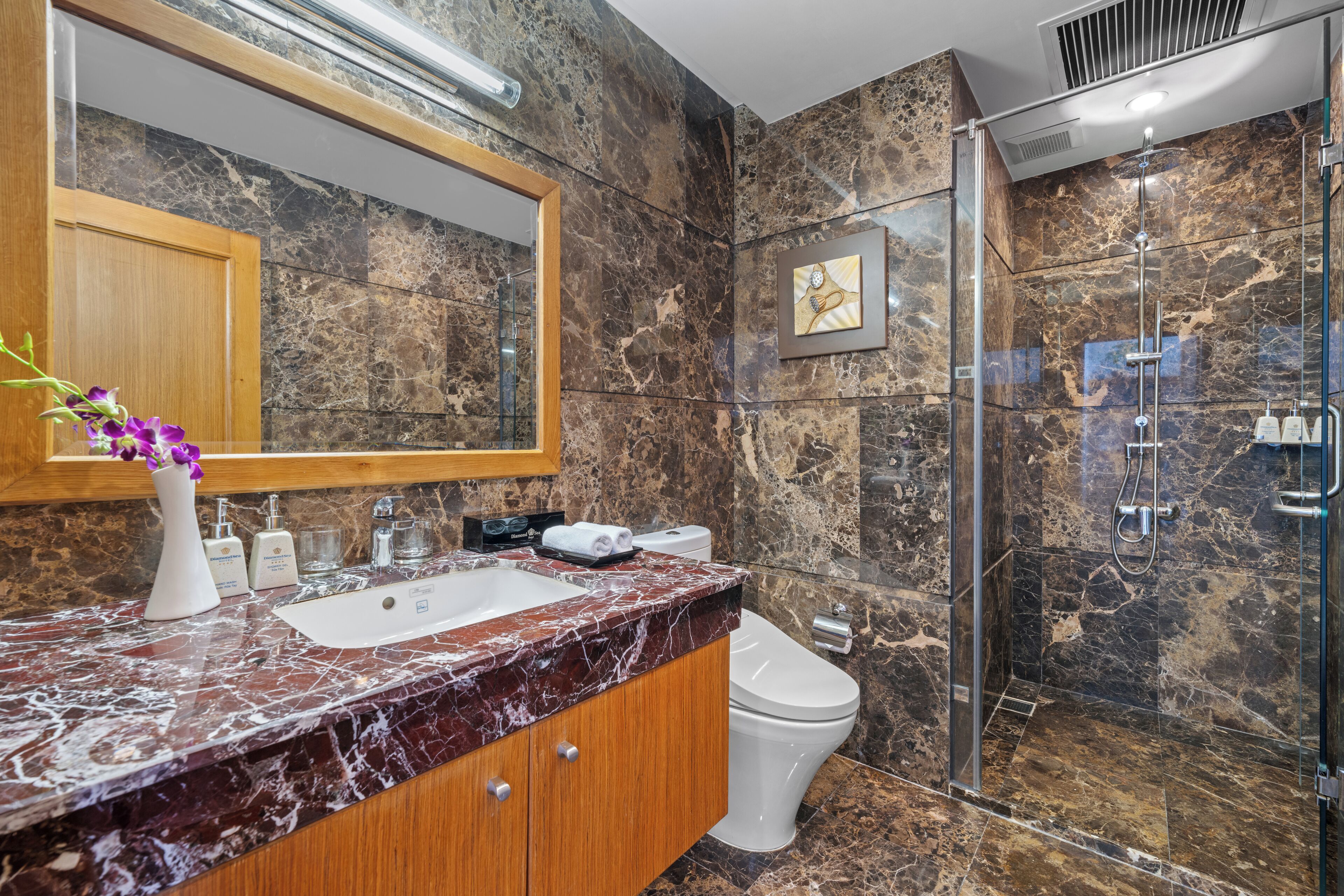 A bathroom with a marble sink, a toilet, and a glass-enclosed shower.