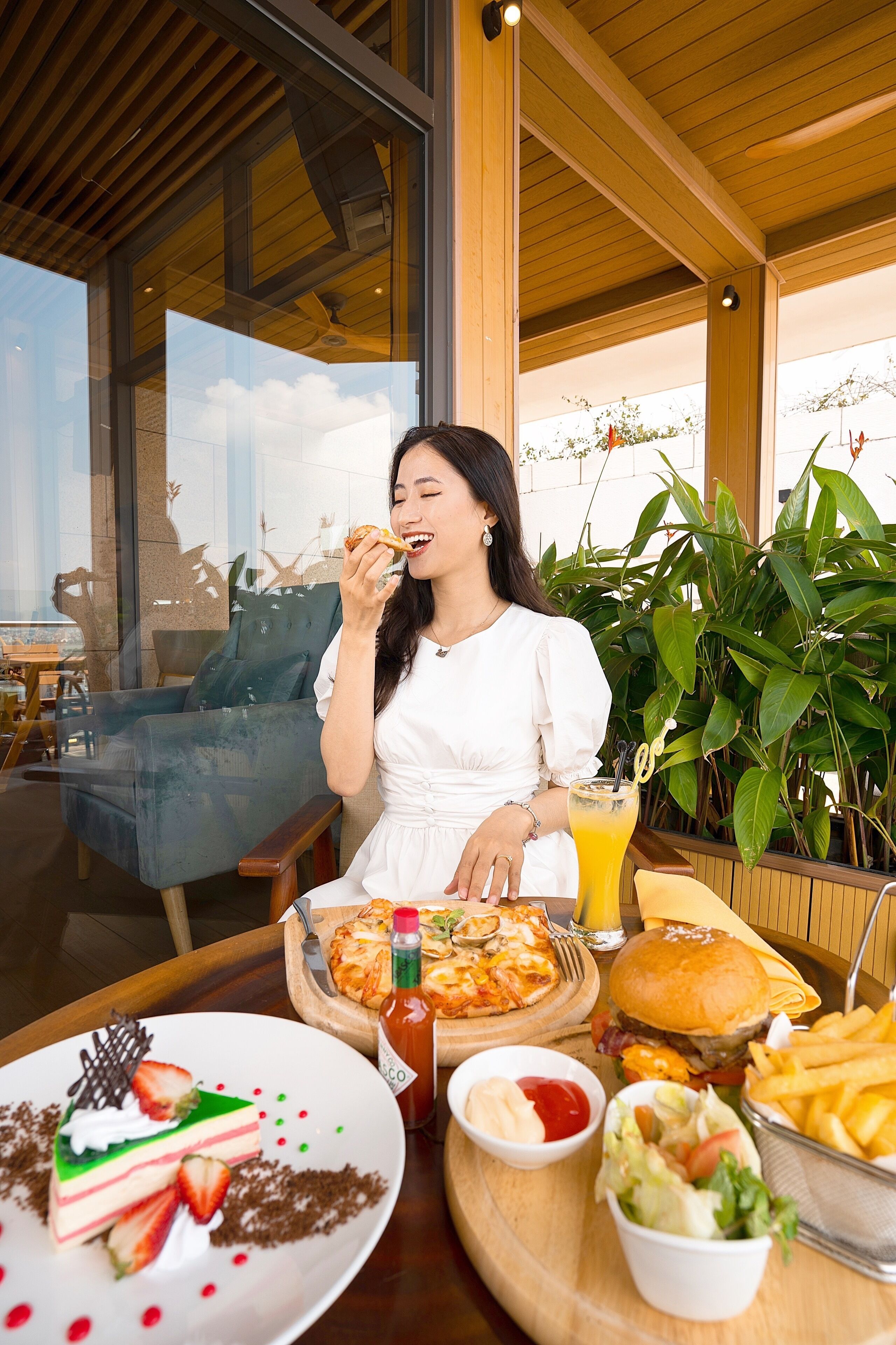 A dining table with a variety of food items including a slice of cake, a burger, fries, and a salad.