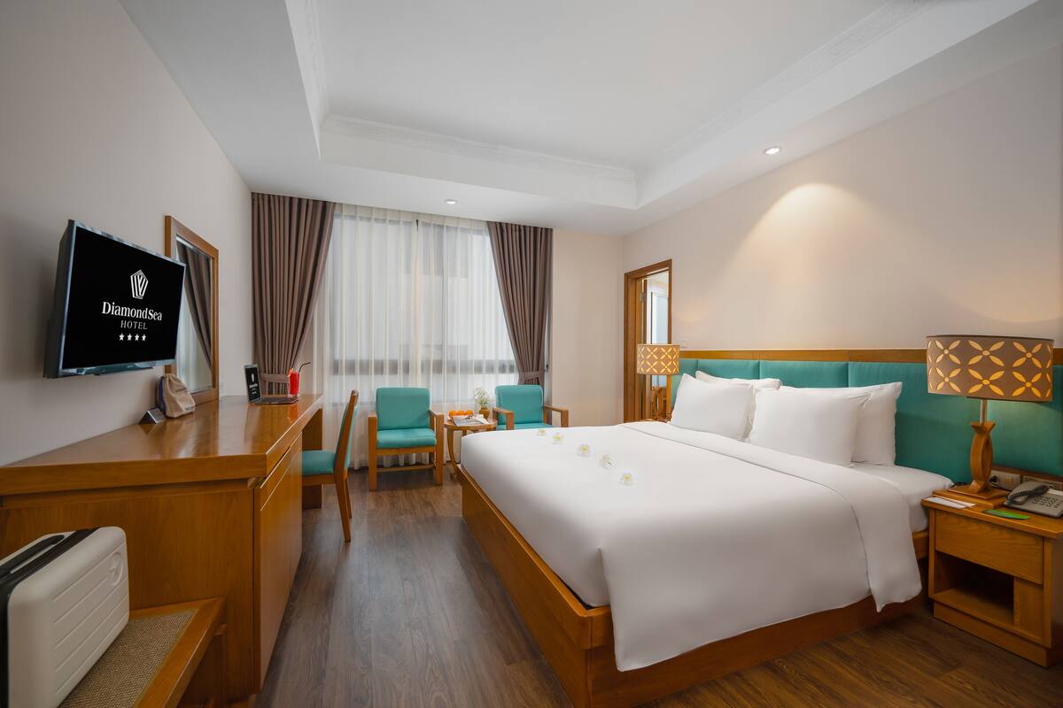 Una habitación de hotel con una cama, un escritorio, un televisor, una silla y una mesita de noche.