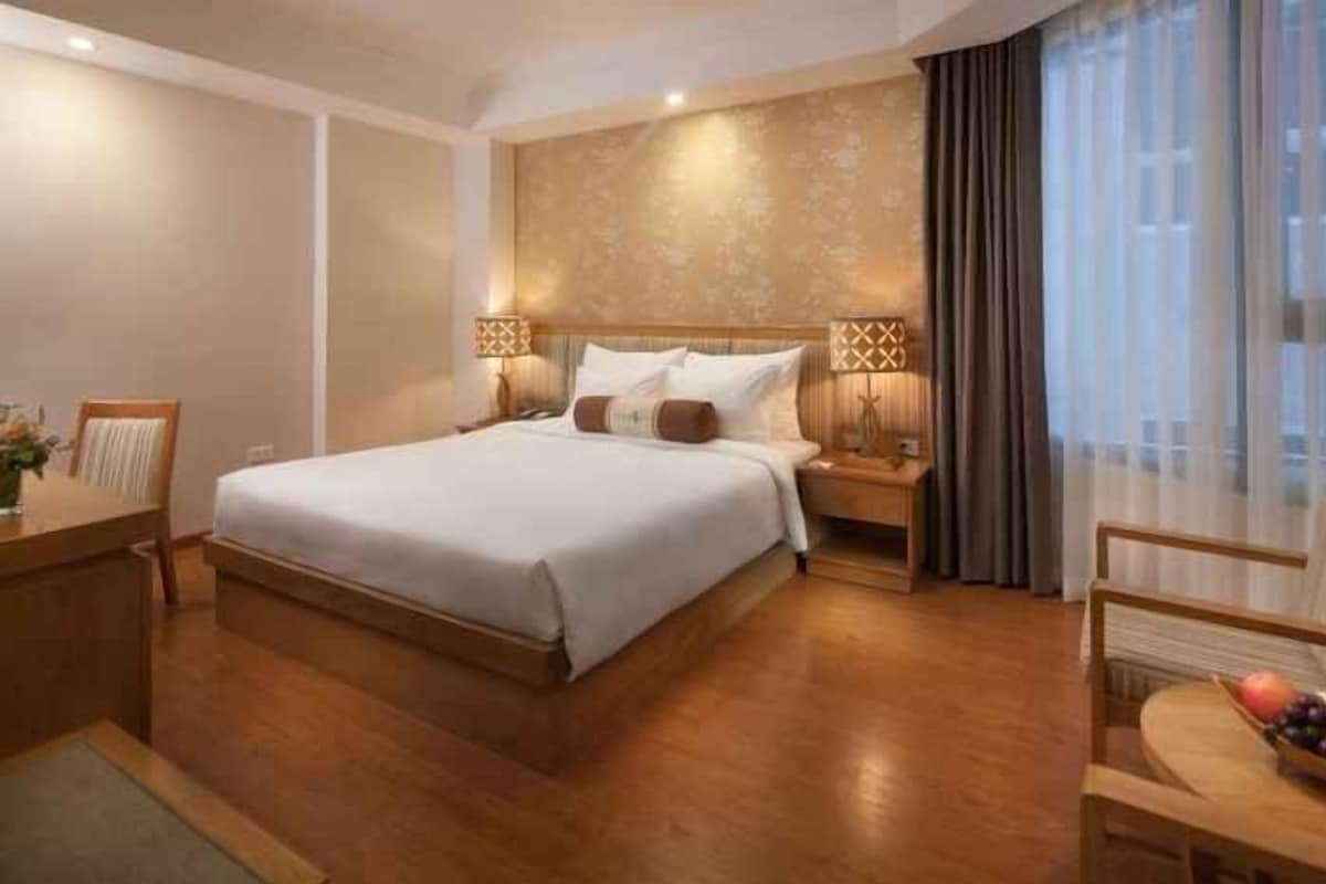 Ein Hotelzimmer mit einem großen Bett, Nachttischen, einem Schreibtisch und einem Stuhl.