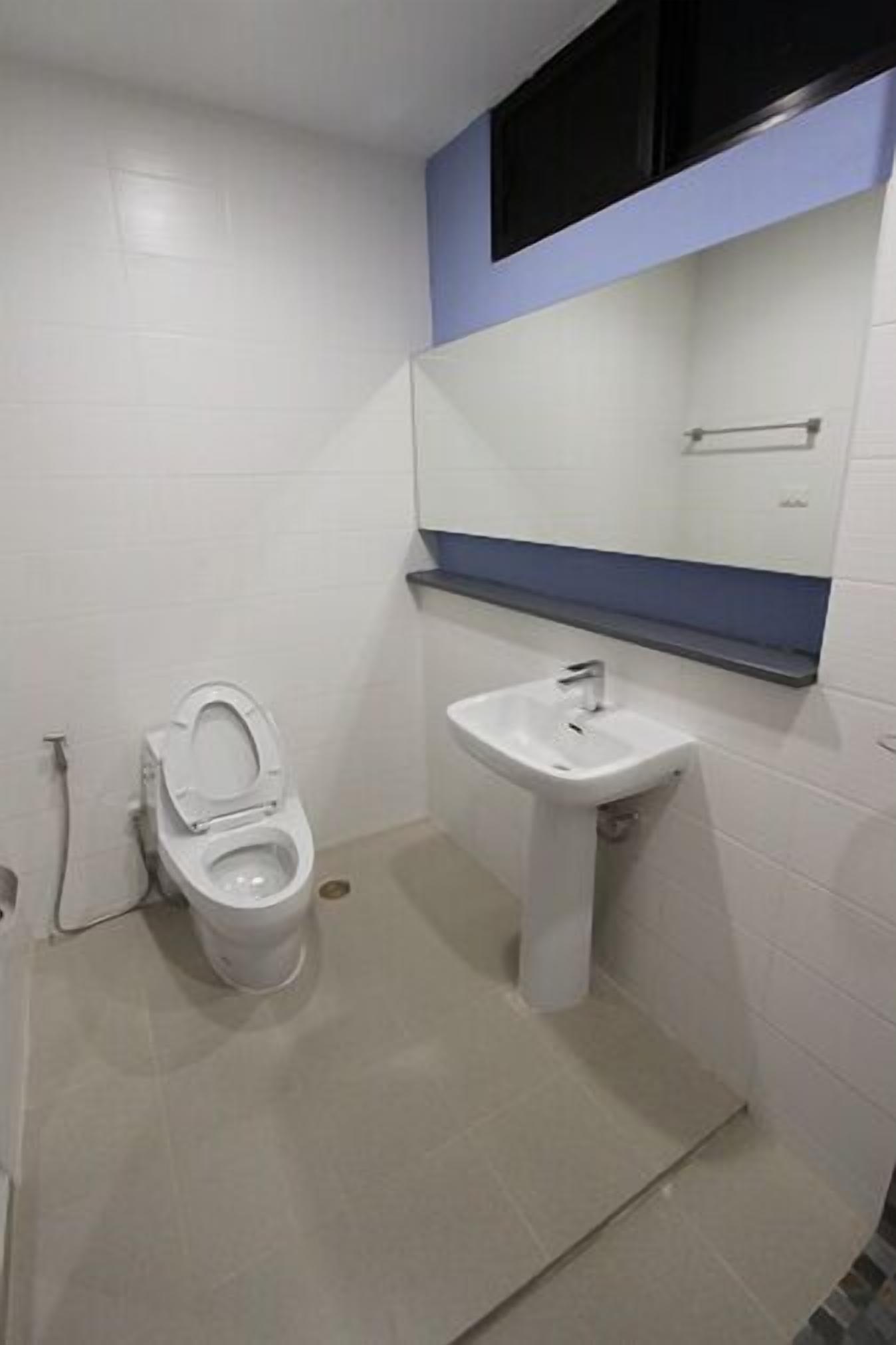 A small, clean bathroom with a toilet, sink, and mirror.