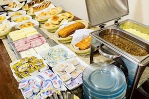 Buffet amb diferents aliments, incloent carns, formatges i pastissos.