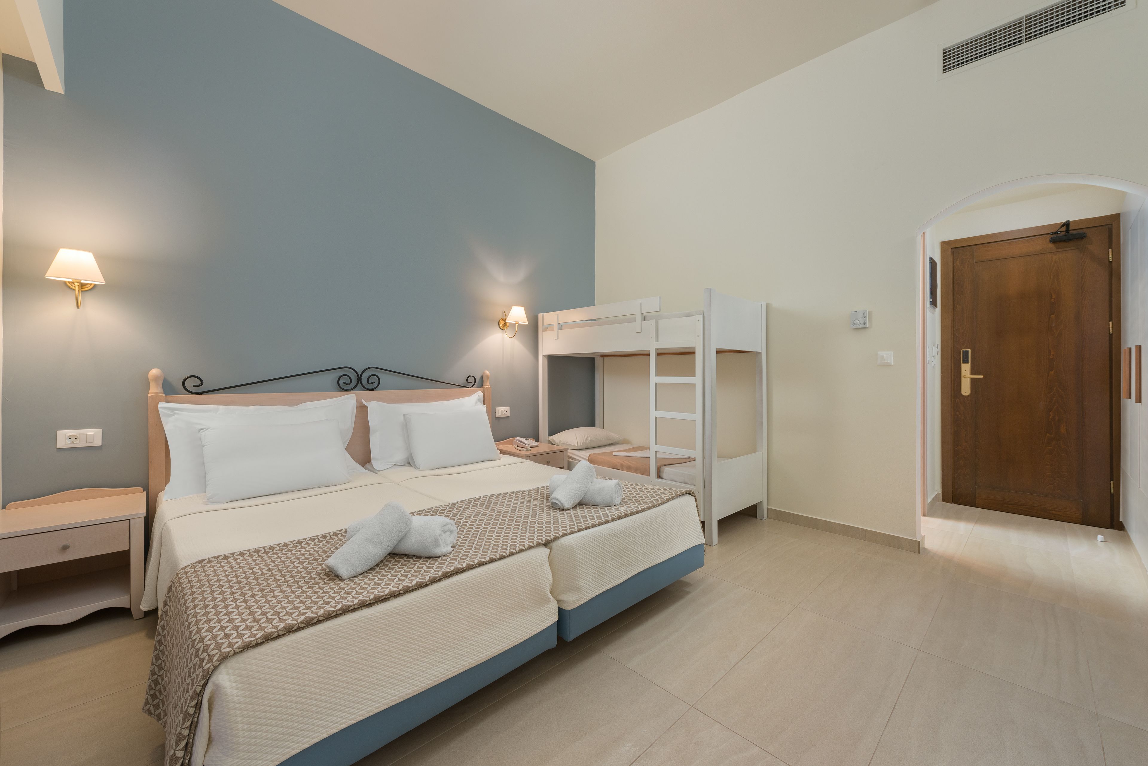 Een slaapkamer met een bed, nachtkastjes, een slaapbank en een deur.