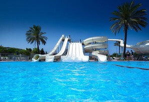 Parque acuático con múltiples toboganes y una piscina.