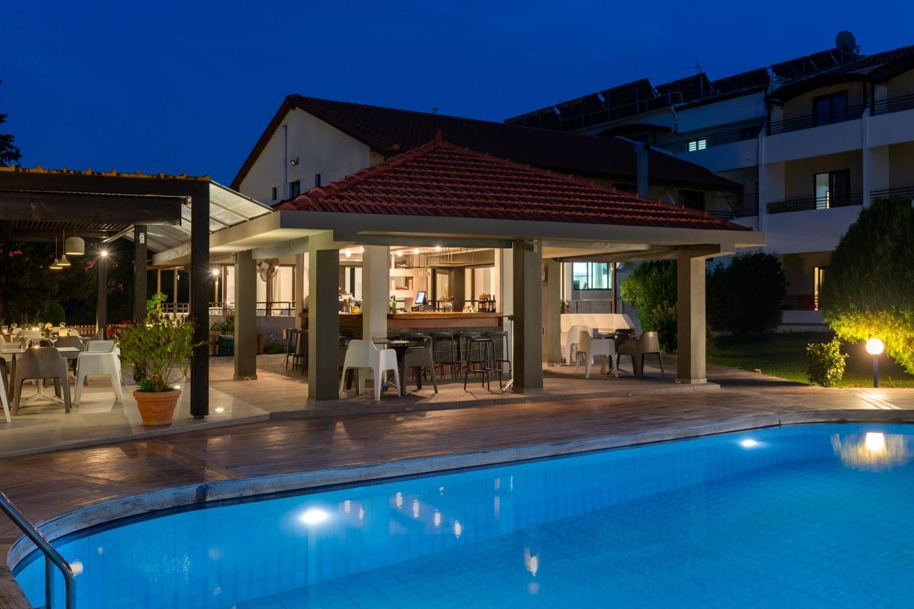 Un área junto a la piscina con una zona de estar techada, un bar y la piscina.