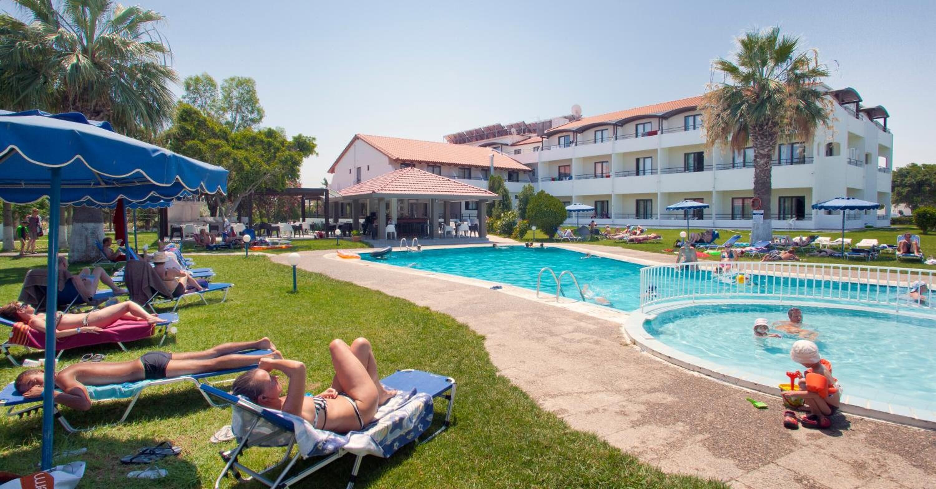 A poolside area with lounge chairs, a swimming pool, and a building with balconies.