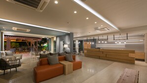 A modern lobby with a reception desk, seating area, and a view of the outdoors.