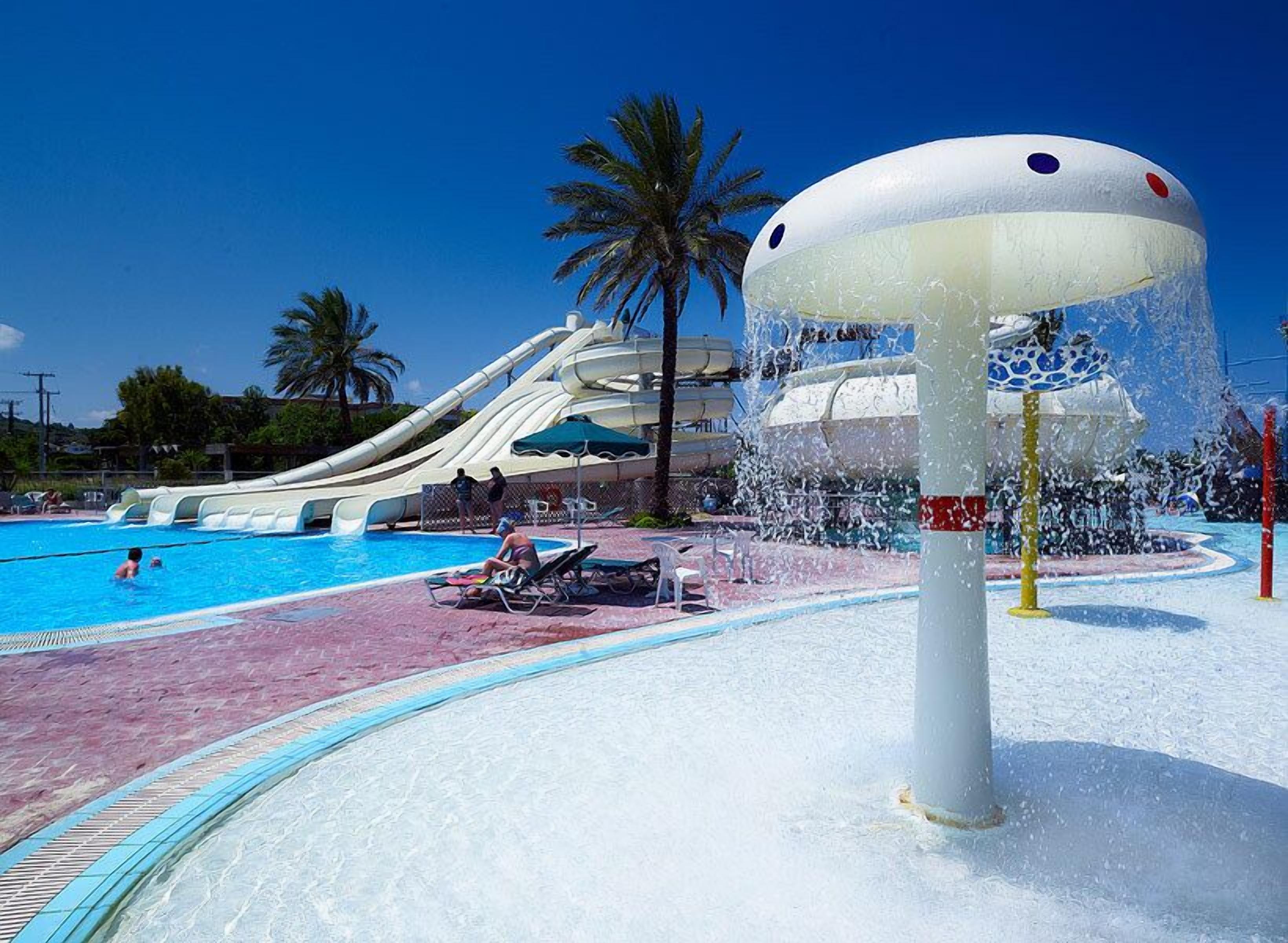 A water park with a large water slide, a pool, and lounge chairs.