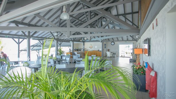 A spacious indoor area with high ceilings, a bar area, and seating arrangements. - Hotel Village Soleil (Le Gosier)