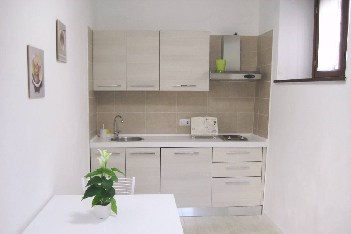 A compact kitchen with a sink, cabinets, and a small window.