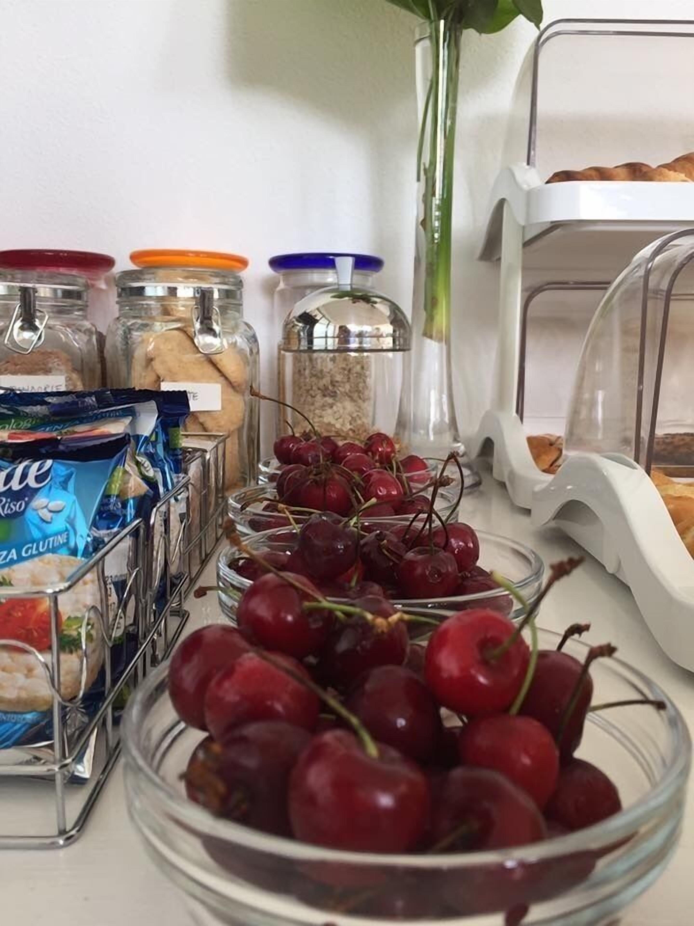 A kitchen counter with jars of spices, a bowl of cherries, and a bag of Riso pasta.