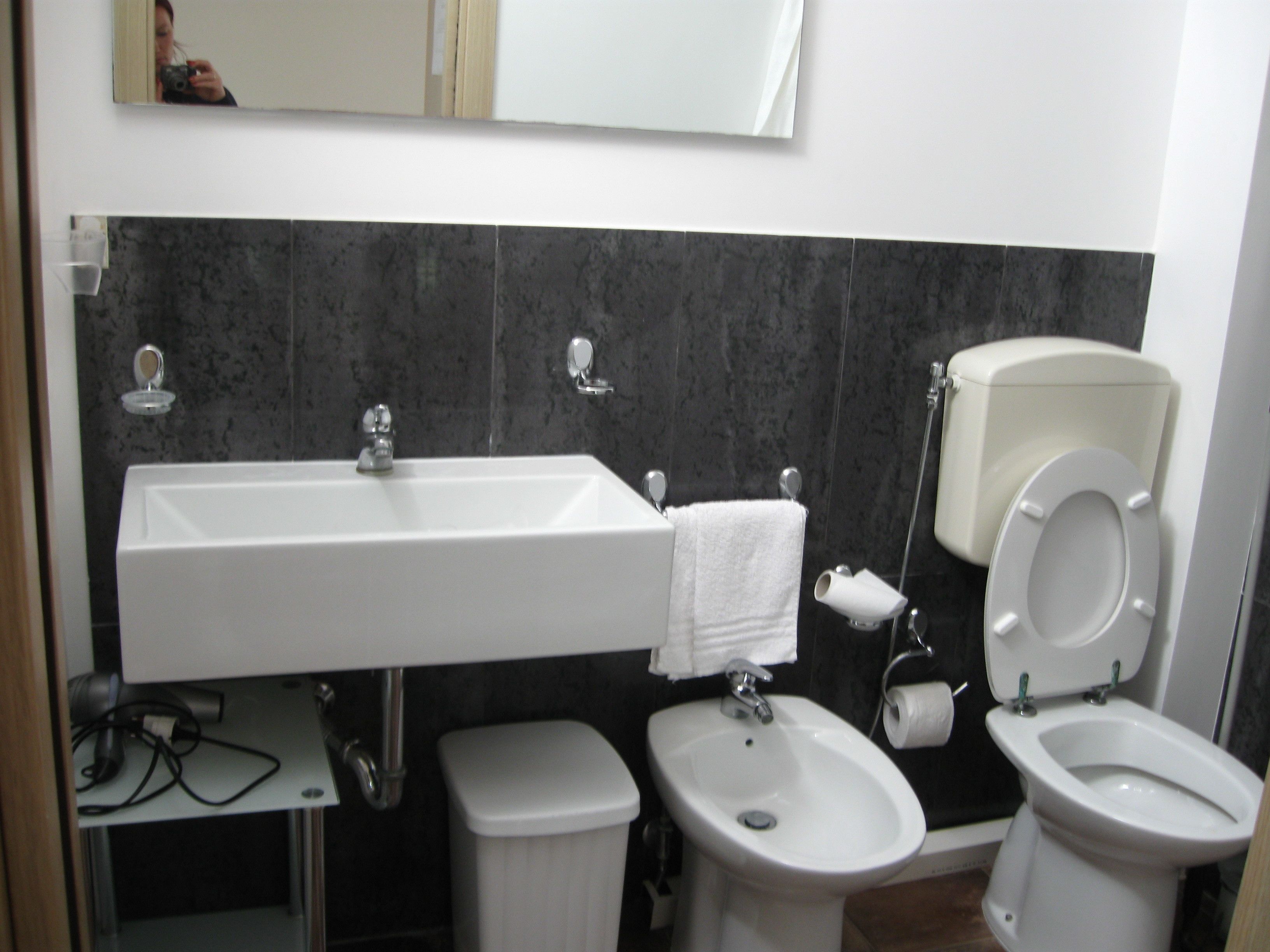 Un bagno con lavandino, bidet, wc e uno specchio.