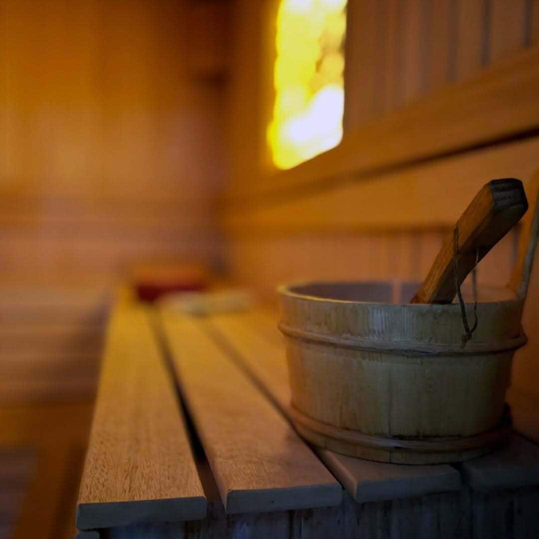 Un banco de madera con un cubo de madera rústico y una cuchara de madera encima.