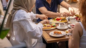 Un grupo de personas cenando al aire libre en una mesa con varios platos y bebidas.