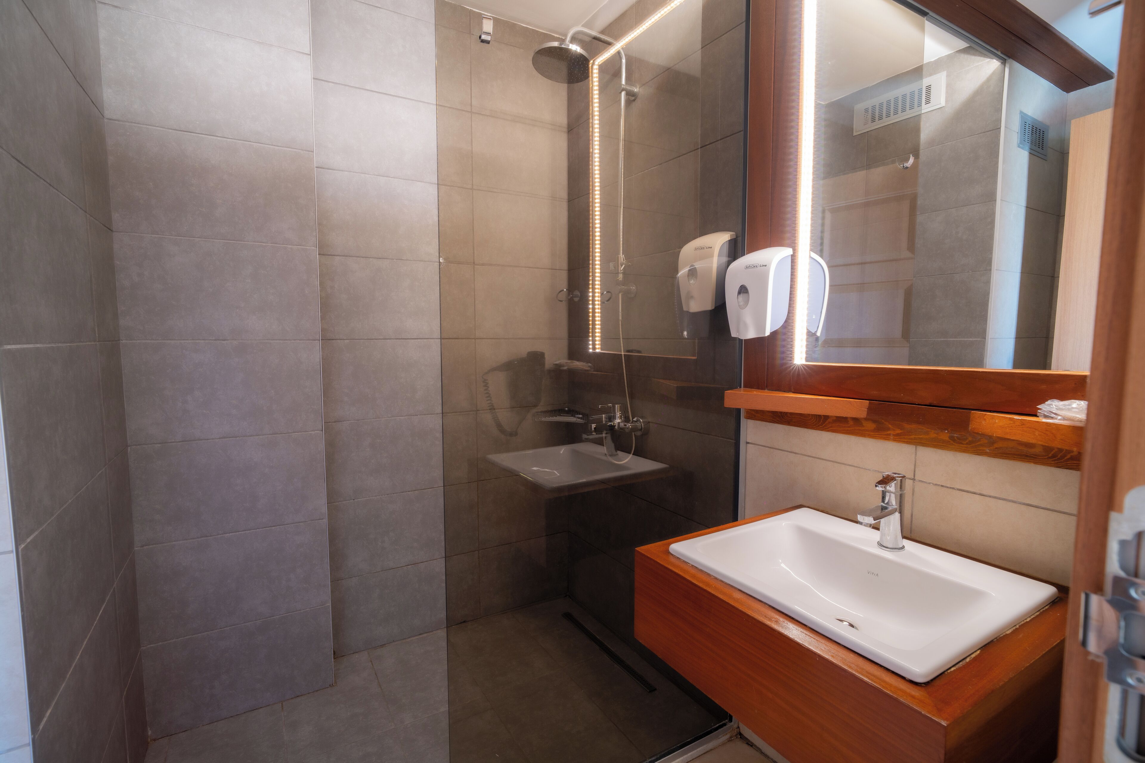 A modern bathroom with a glass-enclosed shower, a wooden vanity with a sink, and a mirror.