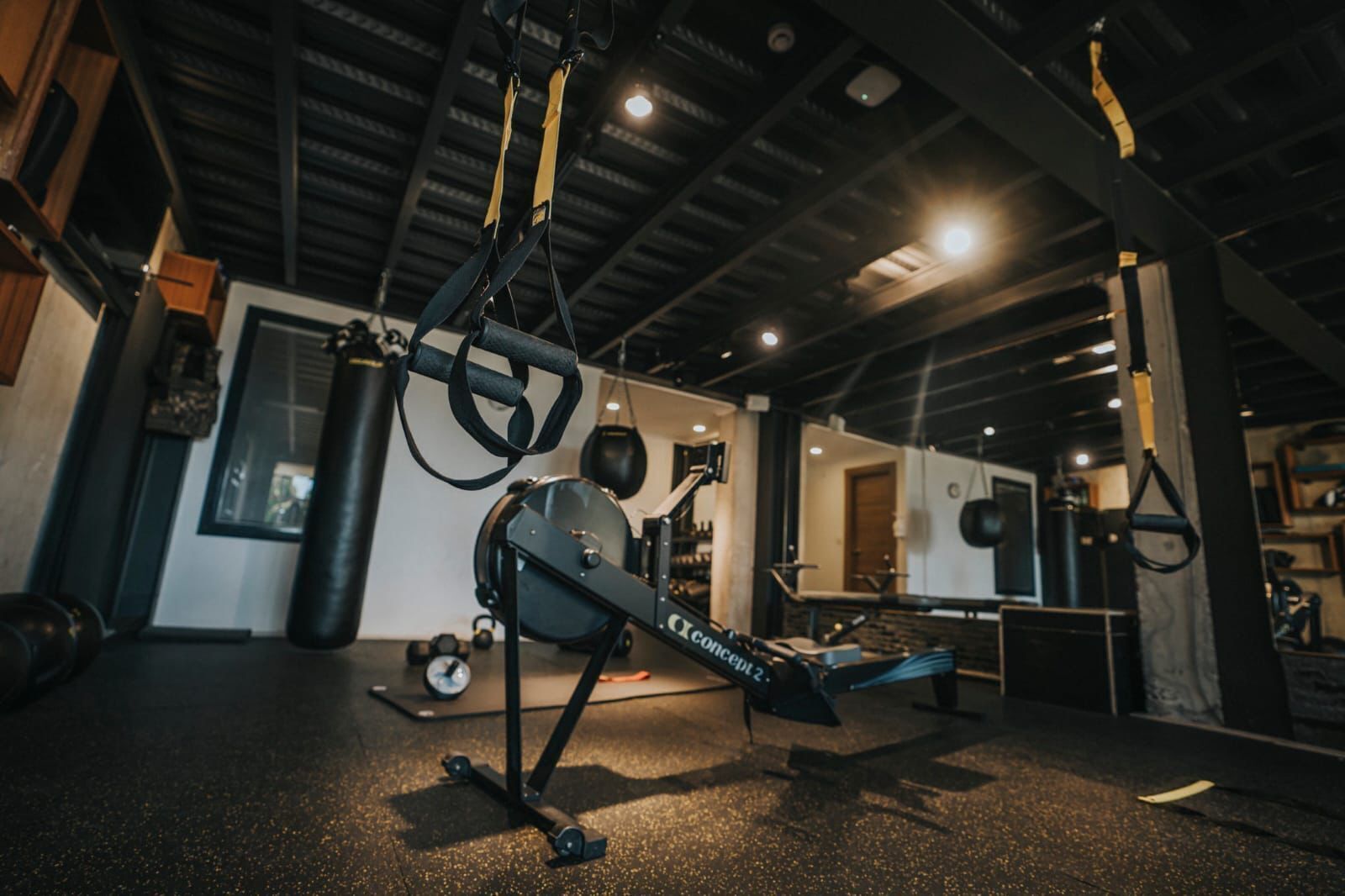 A gym with exercise equipment, including a rowing machine, kettlebells, and a punching bag.