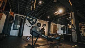 A gym with exercise equipment, including a rowing machine, kettlebells, and a punching bag.