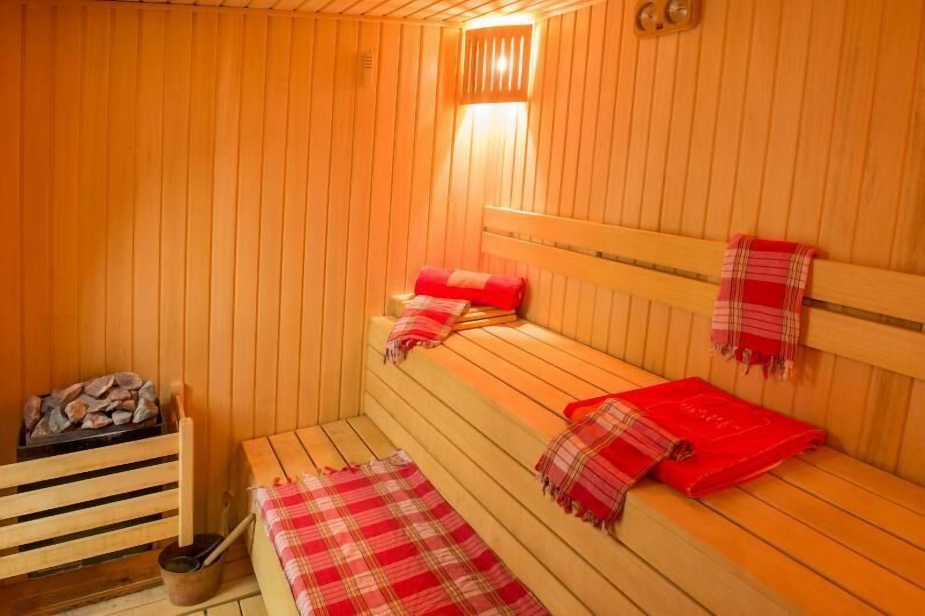 Eine Holzsauna mit Bänken, einer Sitzbank und einem kleinen Holztisch mit Schüssel und Stock.
