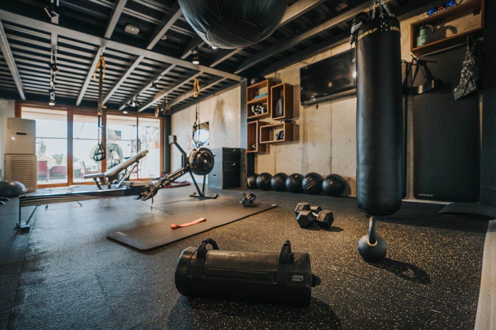 Ein Fitnessstudio mit Trainingsgeräten, einem Boxsack und einem Rudergerät.