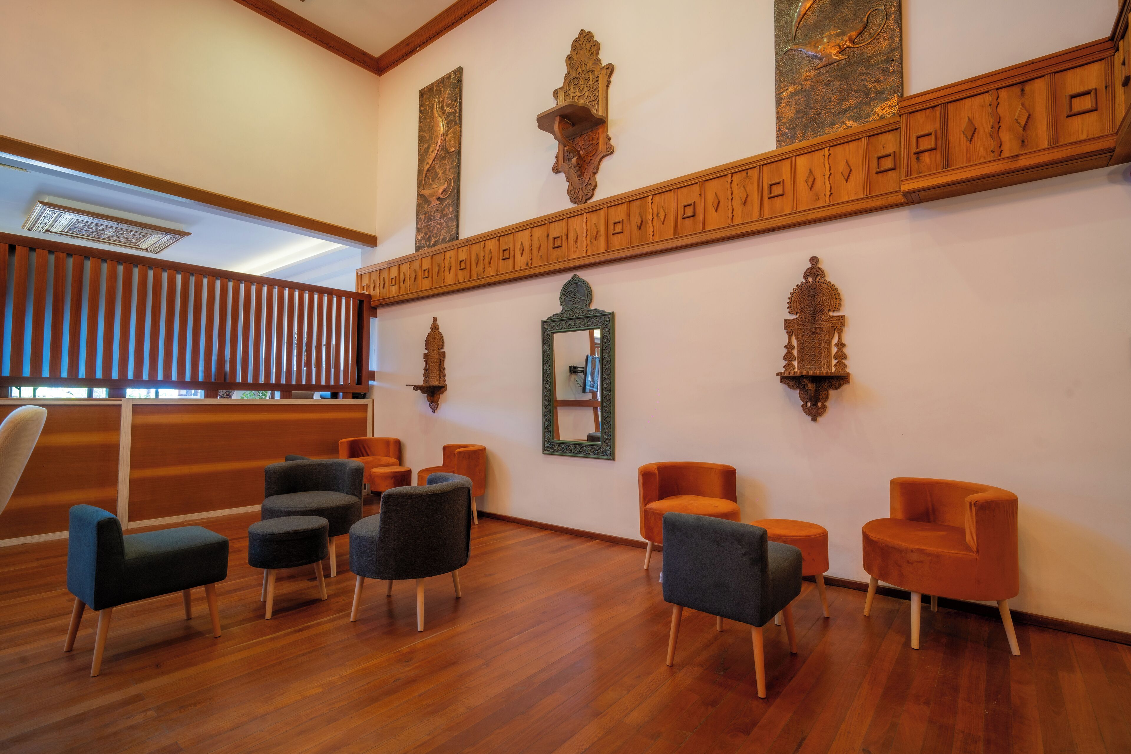 A lobby with wooden flooring, a reception desk, and several seating areas with modern chairs.