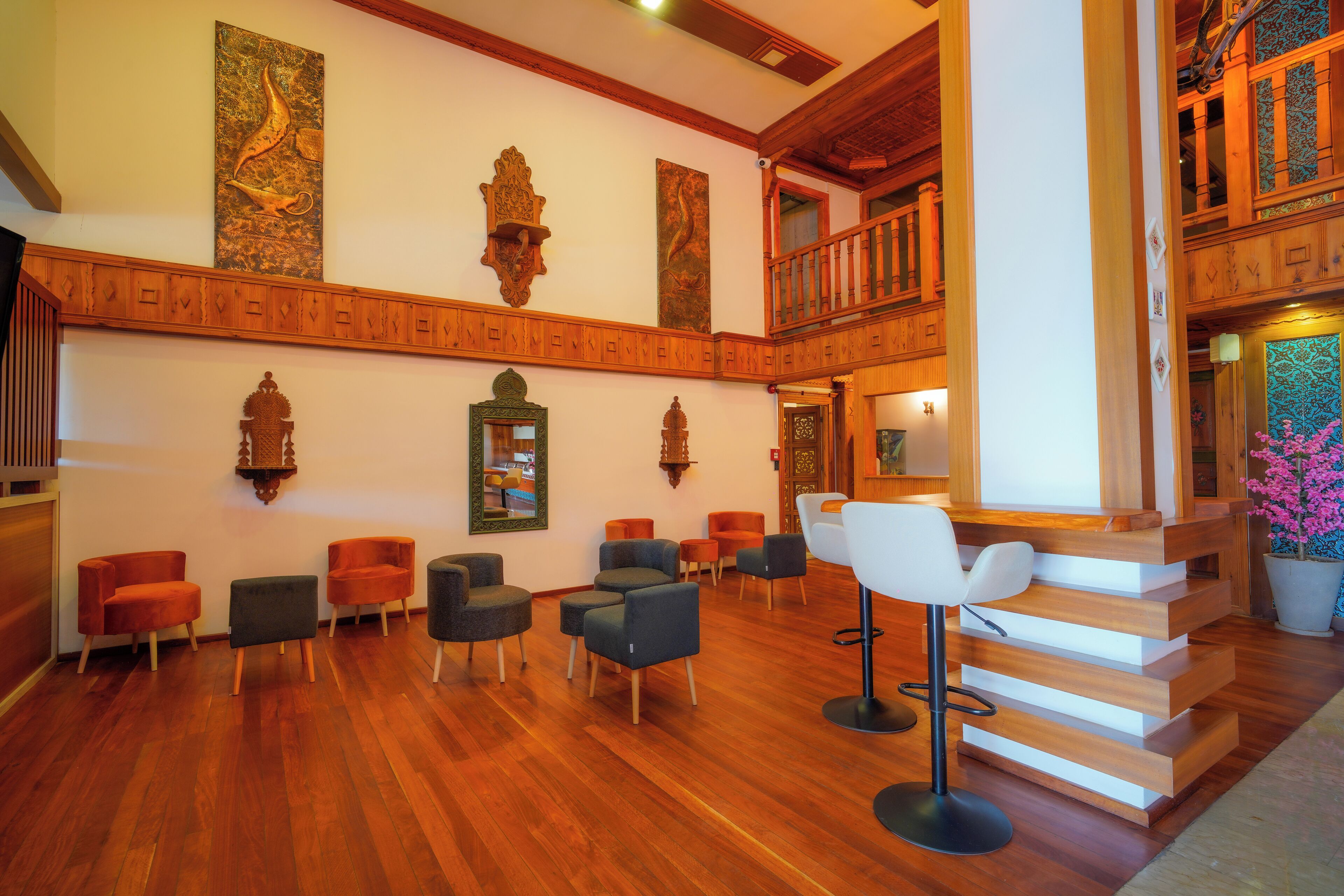 Un vestíbulo con una escalera de madera, varias zonas de estar y paneles decorativos en la pared.