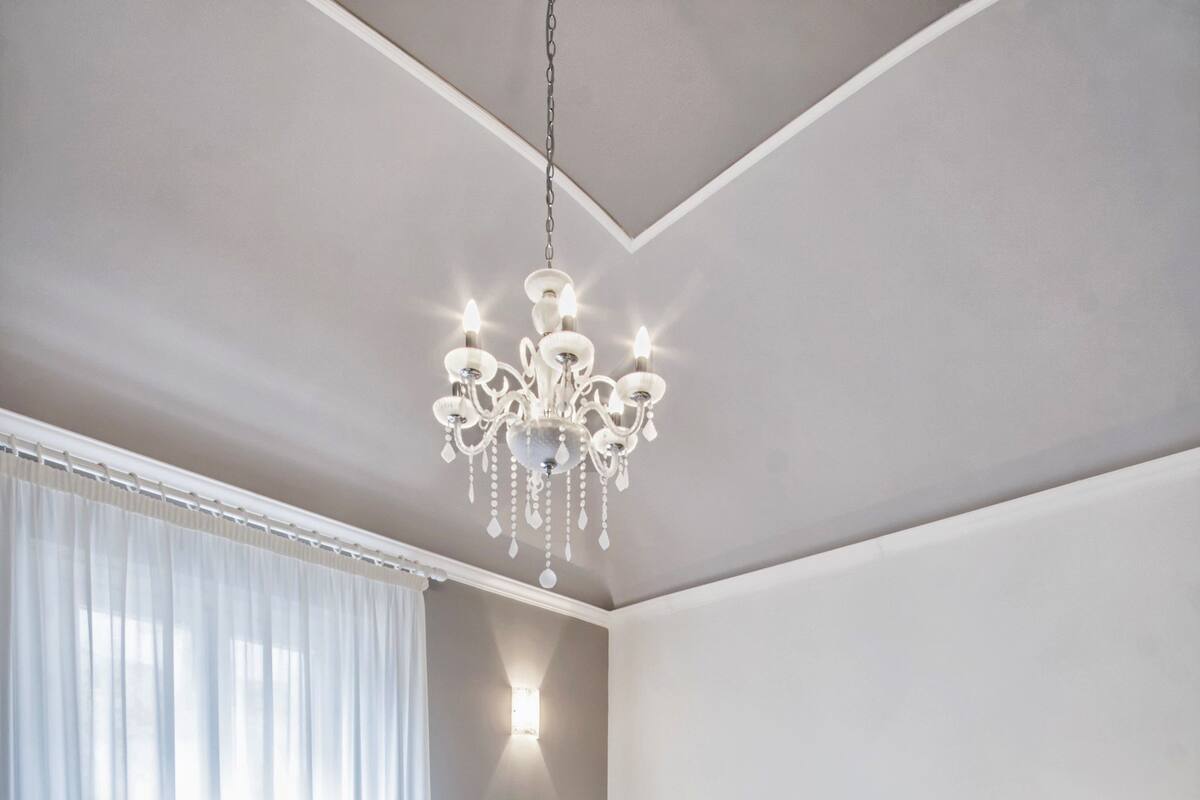 A modern bedroom with a large bed, a chandelier, and a nightstand.