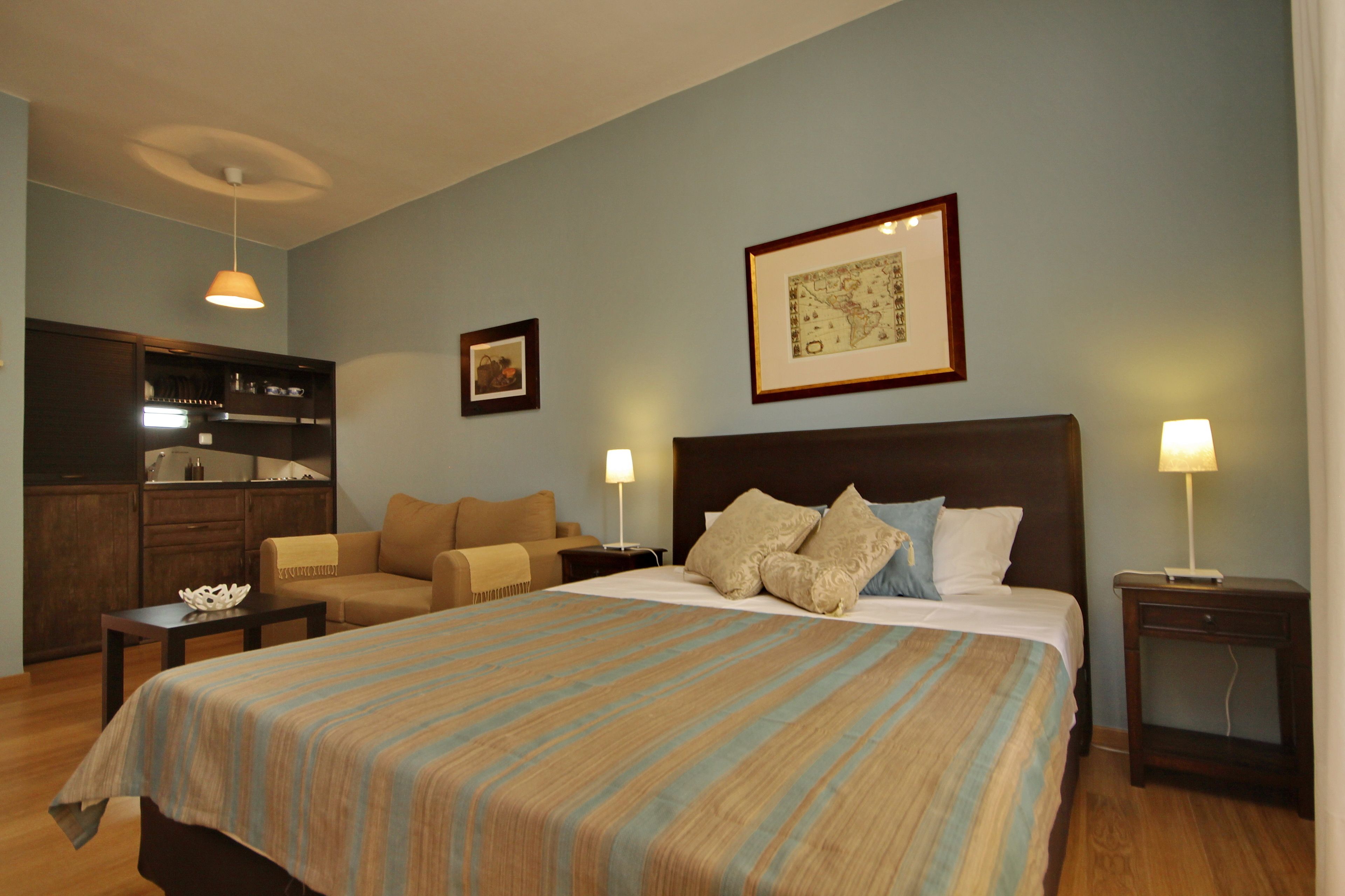 Ein Hotelzimmer mit einem großen Bett, einer Sitzecke, einem Schreibtisch und einer Küchenzeile.