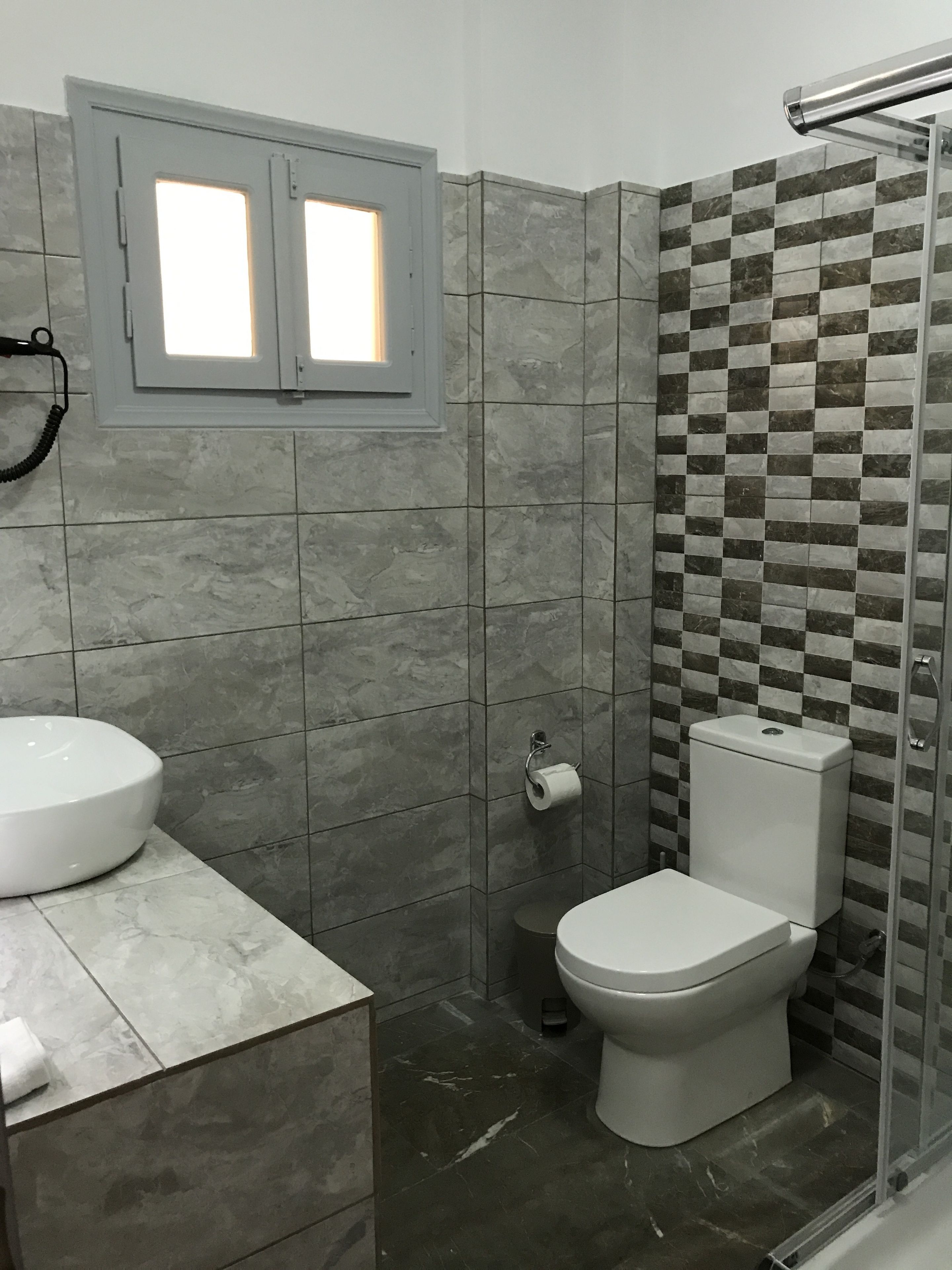 A bathroom with a toilet, sink, and shower.