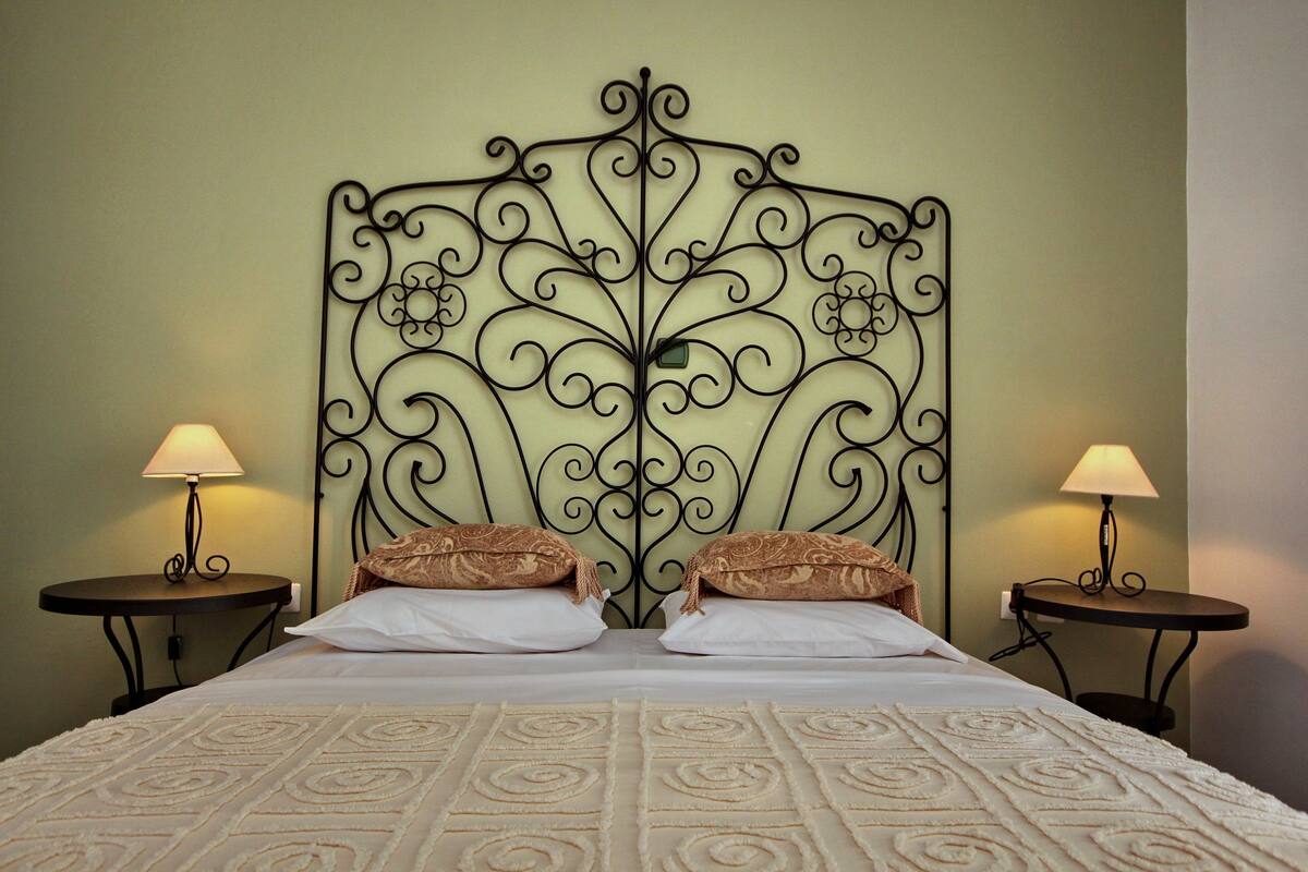 A bed with a decorative metal headboard, two bedside tables with lamps, and a patterned bedspread.