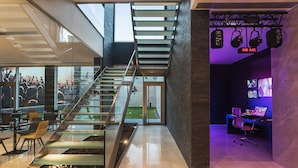 Un interior moderno con una escalera de cristal, una cabina para DJ y vistas a un espacio exterior.