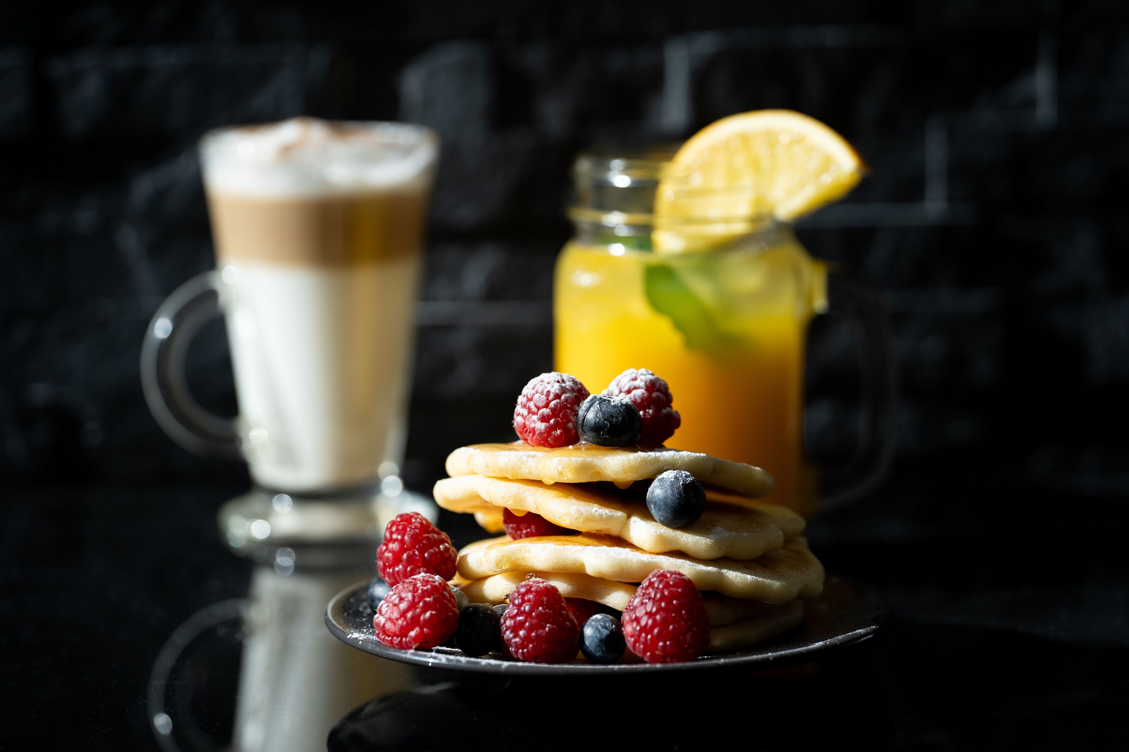 Un plato de postre con gofres, bayas y un vaso de café helado.