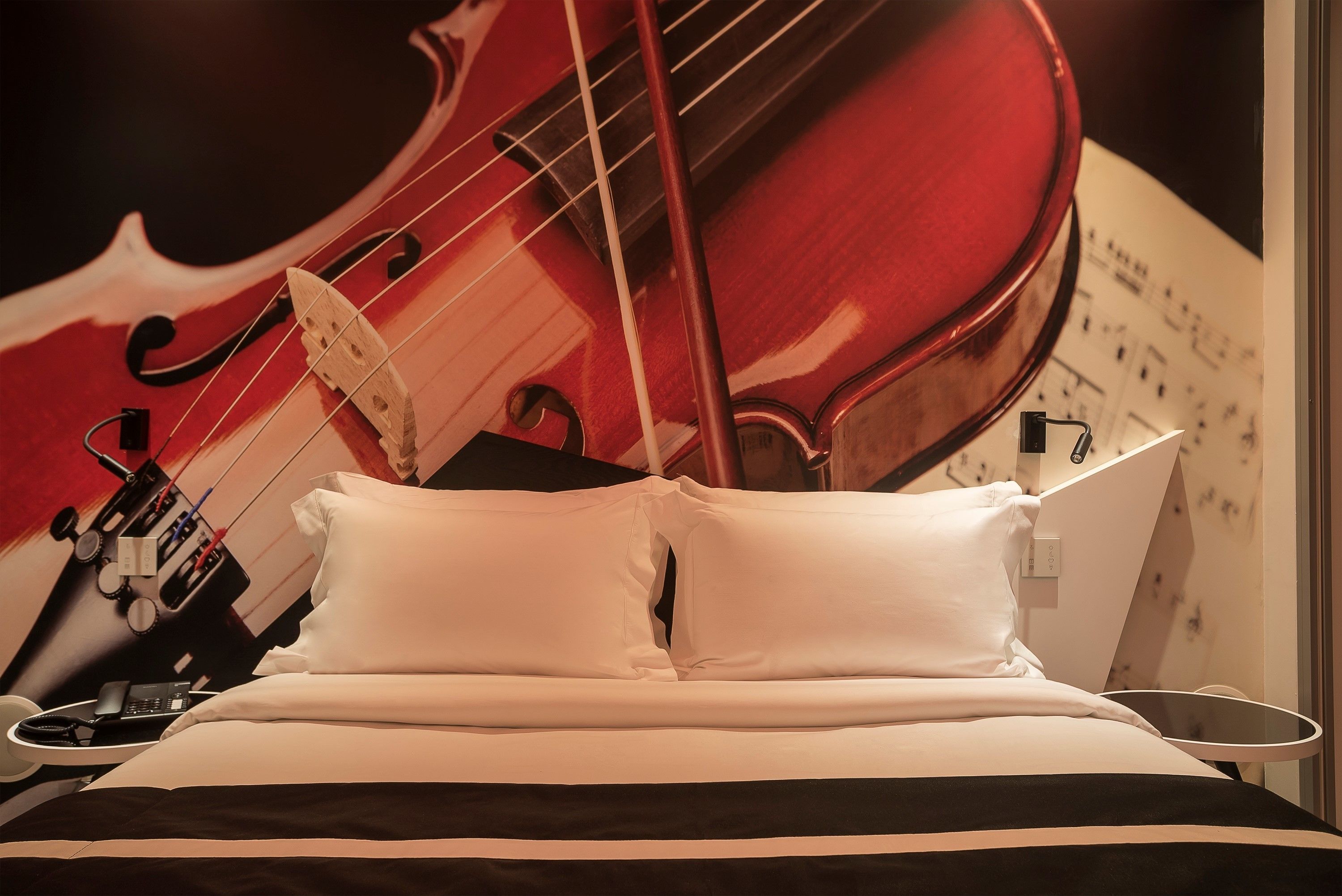 A bed with white pillows and a black and white striped bedspread.