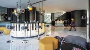 Un moderno vestíbulo de hotel con recepción, zona de bar y asientos.
