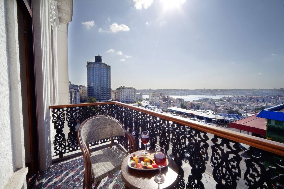 A balcony with a dining table, a chair, and a view of the cityscape.