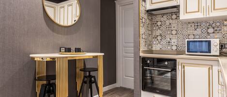 A modern kitchen with white cabinetry, a microwave, and a round mirror.