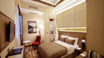 A hotel room with a bed, a TV, a desk, a chair, and a bathroom door.